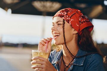 Lifestyle woman in modern boho-western denim street style drinking a cold beverage, enjoying...