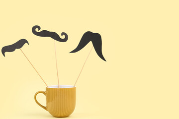 Paper mustaches on wooden sticks in cup against color background