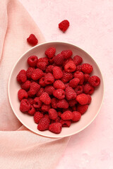 Bowl with fresh raspberries on pink background