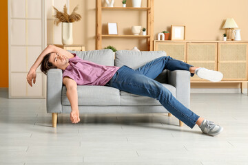 Weary young man lying on sofa at home
