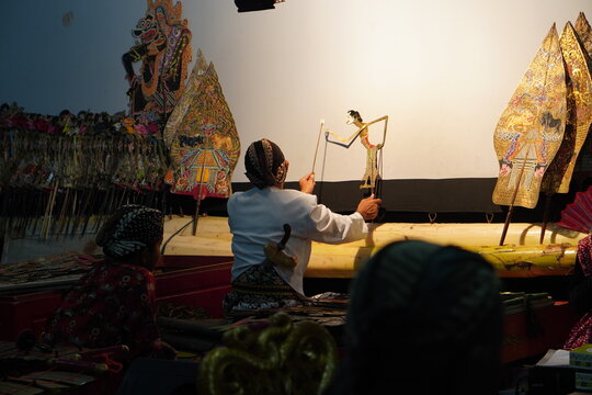 A traditional Javanese puppeteer, or dalang, performs a wayang kulit shadow puppet show on stage