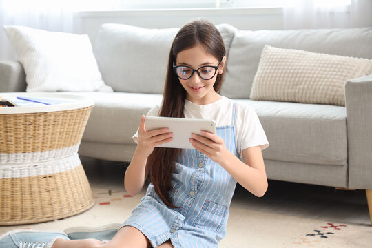 Little schoolgirl using tablet computer at home