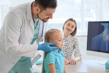 Obraz premium Male endocrinologist examining thyroid gland of little girl and her mother in clinic