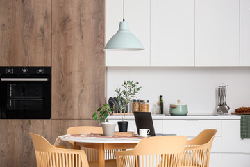Cup of coffee, houseplants and modern laptop on table in dining room