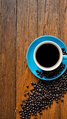 Overhead view of hot black coffee in blue ceramic cup with scattered roasted beans on rustic wooden surface. Food and drink concept
