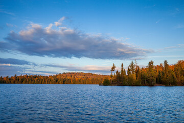 Blue trout lake with trees and hills in autumn color at sunset in northern Minnesota