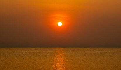 Obraz premium Beautiful photography view golden sun orang setting over calm sea, peaceful atmosphere and soft gradient sky create sense of serenity and timeless beauty perfect elaxation, travel, and nature