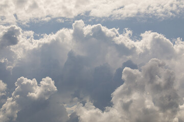 Thick, billowing cumulus clouds tower in the sky, partially illuminated by sunlight, creating a dramatic and dynamic weather scene.