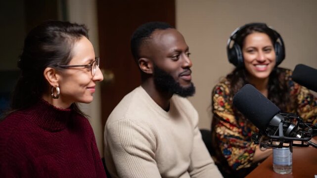 A diverse group of friends smile radiantly while seated in a podcast studio, embodying the spirit of collaboration, conversation, and connection through their joyful expressions.