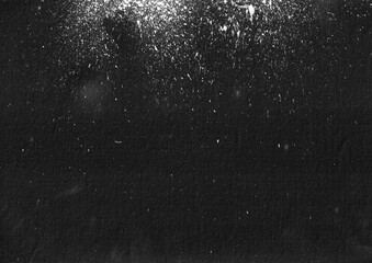 White paint splatter on black background.  Grunge dusty particle overlay design. Rough weathered backdrop.