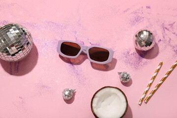 Disco balls with sunglasses, coconut and straws on pink background