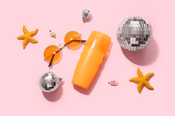 Disco balls with sunscreen, sunglasses and starfishes on pink background