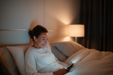 Woman sitting on a bed looking at her phone