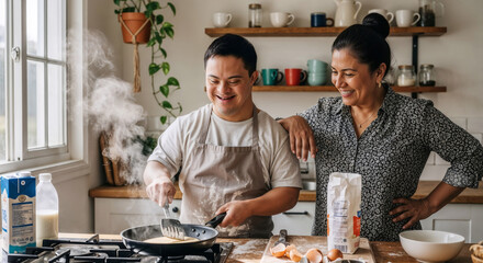 Happy young caucasian man with down syndrome wearing an apron and cooking delicious crepes on the stove with his latina mother watching him in a domestic kitchen