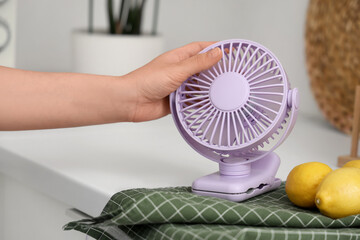 Woman putting small electric fan on table, closeup
