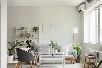 Interior of living room with comfortable sofa, armchair and table near white wall