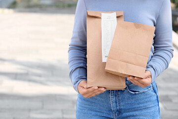 Woman with paper bags outdoors. Food delivery service