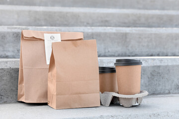 Paper bags with coffee cups on stairs outdoors. Food delivery service