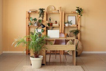 Interior of office with workplace, shelf unit and green plants