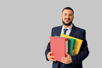 Handsome businessman with folders on light background