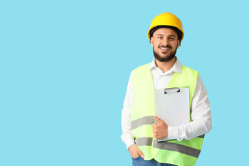 Fototapeta premium Male architect with clipboard on blue background