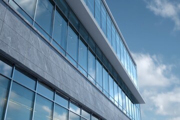 Building exterior features glass windows framed by concrete panels under a sky with clouds
