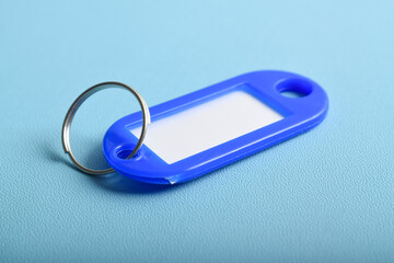 Blue plastic key tag isolated on light blue background