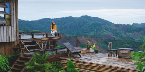 A woman sitting on wooden terrace and looking at a mountain view