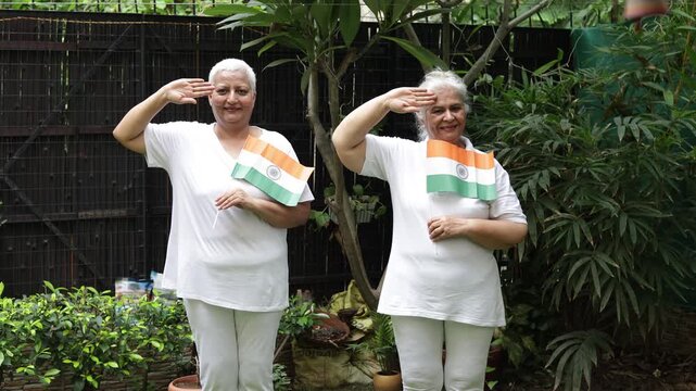 Two Proud patriotic senior women holding indian flag saluting and celebrating Independence day or Republic day. 15th August, 26 January. People of india. Patriotism. 4k