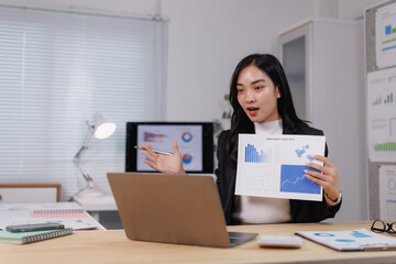 Asian businesswoman presenting financial charts during video call in office