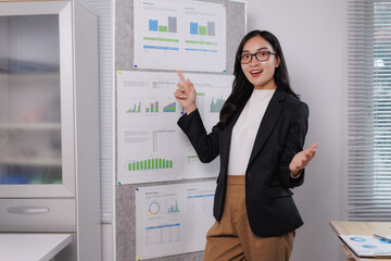Asian businesswoman presenting business data analysis with charts and graphs on a board