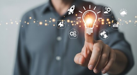 Man touching a light bulb with icons representing business and innovation on a gray background shirt