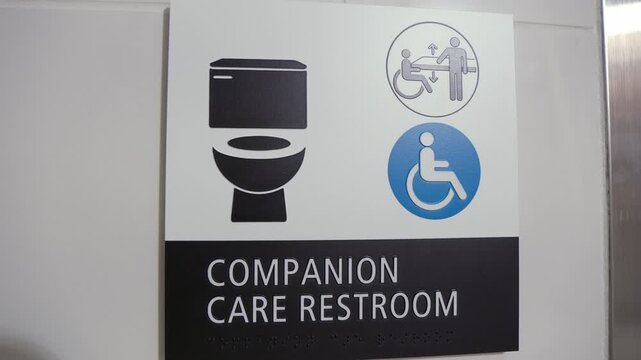 Sign with pictograms on a restroom for people with disabilities and companion care. Ideal for themes of accessibility, inclusion, public facilities, and support.