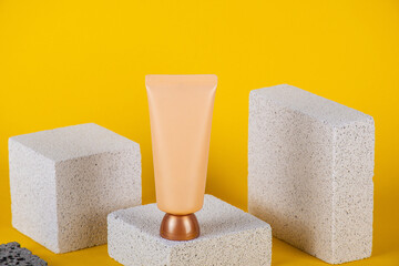 Plastic white tube for cream or lotion. Skin care or sunscreen cosmetic with stylish props on yellow background.