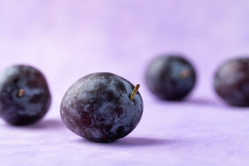 Fresh blue plum fruit on purple background