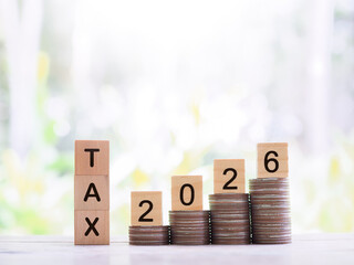 Wooden blocks with the word TAX and Number 2026 on stack of coins. The concept about saving money...