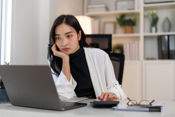 Businesswoman calculating tax using calculator and laptop in office