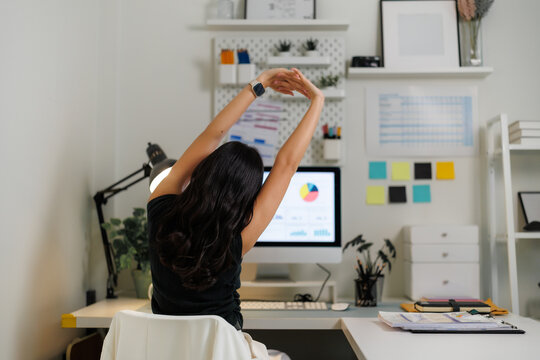 Office worker stretching arms at desk after work on computer