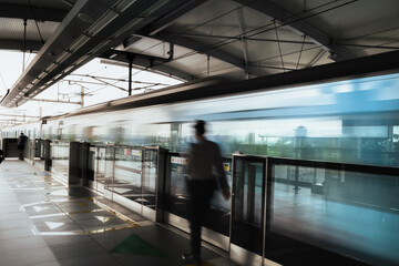 Indonesia mass rapid transit train station platform with motion blur image of fast moving train and security guard passing by