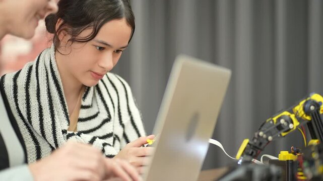 High school students and teachers from diverse cultural backgrounds collaborate in a modern science and technology classroom, using laptops to program robots and explore real-world applications throug