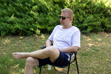 barefoot man sitting on folding chair outdoors