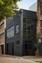 Modern architectural design of a black brick building in an urban setting, featuring large windows and a sleek, minimalist exterior during the daytime