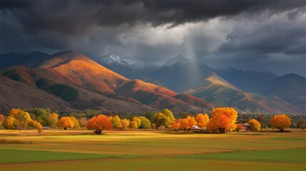 Dramatic autumn landscape with colorful trees in a valley under a stormy mountain sky.