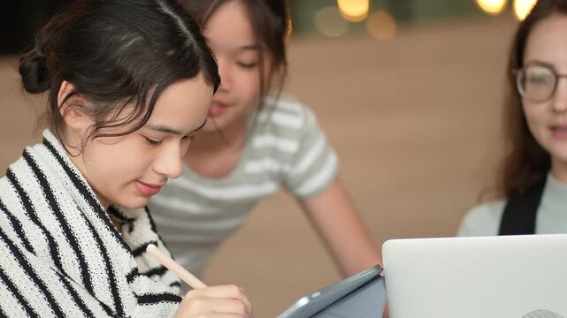 High school girls gather around laptops are taking special classes with specialized teachers with special lessons that enhance skills for preparing for university entrance. Profescer is guideing stude