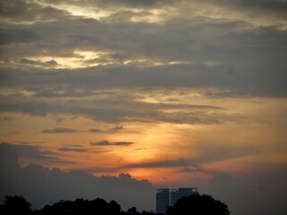 Moody Dusk Sky: Dusky Orange Clouds Embrace Urban Silhouette at Sunset on West Lake in Hanoi, Vietnam