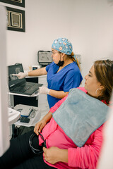 hispanic Dentist showing teeth x ray to patient on laptop in dental clinic