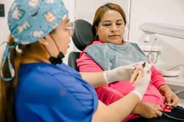 Dentist showing tooth anatomy to patient in clinic