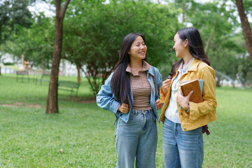 Two female students walking and talking in a university campus park