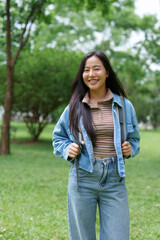 Young woman smiling with backpack in green park