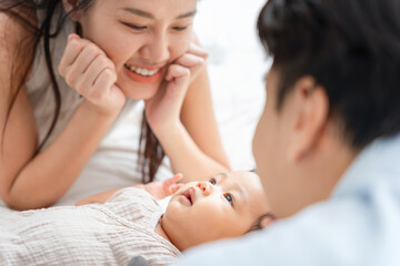 Happy Parents Adoring Their Cute Baby at Home, Asian Mother and Father Playing with Infant Child,...